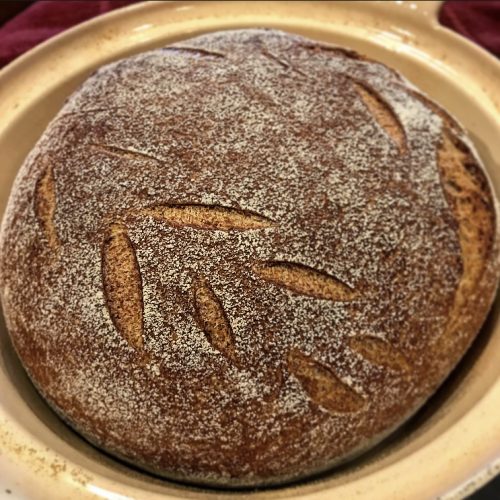 baked chewyy spelt bread with scoring design in dutch oven